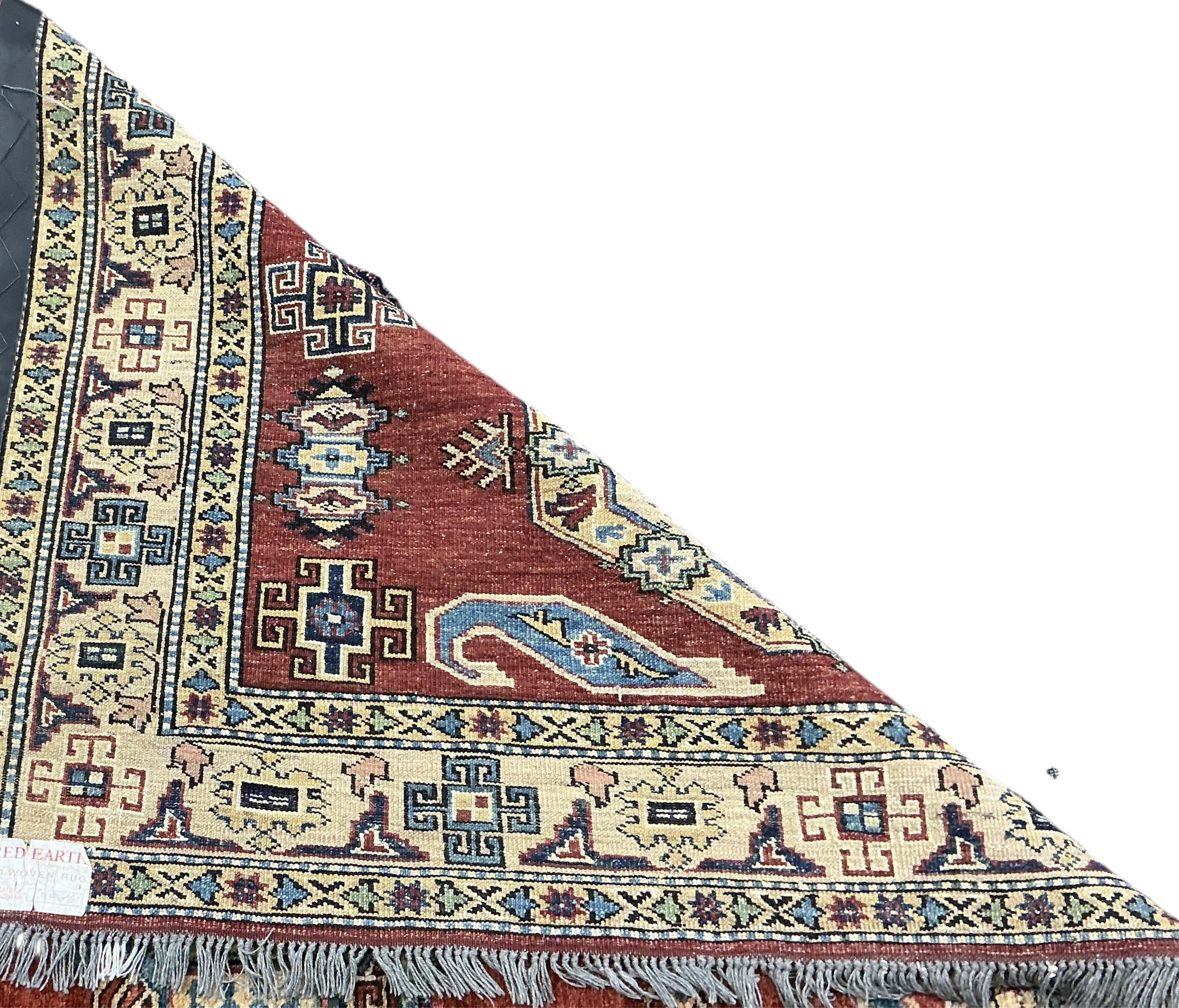 A Caucasian design brick red ground rug, 200cm x 140cm